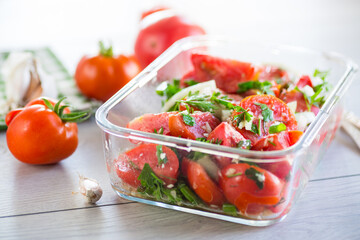 Spicy snack tomatoes with garlic, herbs, seasonings and onions in a glass bowl .