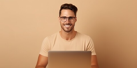 Smiling cute young man in a brown t-shirt and glasses looks into a digital tablet and surfs the internet.
