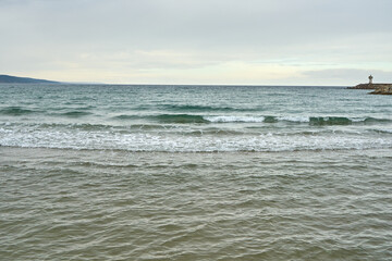 Fototapeta premium Wavy winter sea and a lantern on the horizon