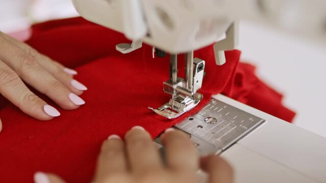 Woman clothing designer sews red fabrics on a sewing machine. Needlework and handmade patchwork hobby.	