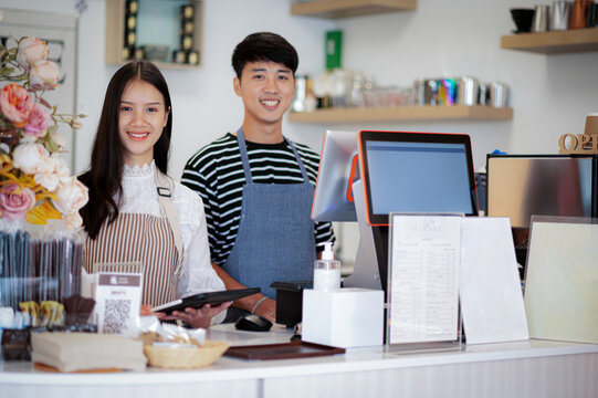 A coffee shop business owner greets customers with a smiling face.