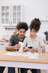 man and woman couple pay electricity and rent bills. African American young married person in...