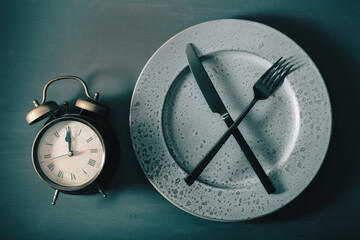 concept of intermittent fasting, ketogenic diet, weight loss. alarmclock fork and knife on a plate