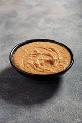 smooth peanut butter in bowl on gray background