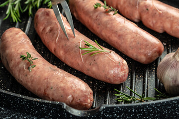 Raw sausages and ingredients on the grill pan ready to cook. Grilling food, bbq, barbecue. place...