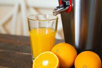 The glass with freshly squeezed orange juice and juicer is a close-up.