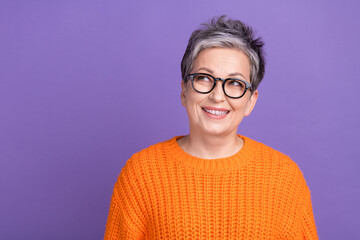 Photo of cute dreamy woman dressed orange sweater eyewear looking empty space isolated violet color background