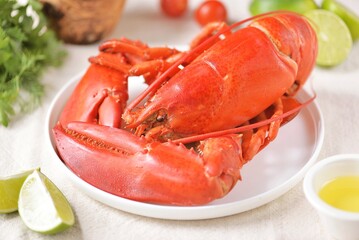 whole boiled lobster on a white plate with lime slices
