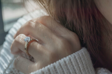 Close up of diamond ring on woman’s finger with sunlight and shadow. Love, valentine, relationship and wedding concept. Soft and selective focus.