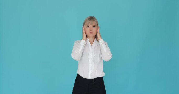 Serious woman is depicted with hands covering her ears on a serene blue background, indicating that she cannot hear anything. Her intense expression portrays her focus on blocking out external sounds.