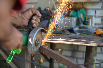 Hands of the master saw the metal with a grinder. metal works in the workshop and Cutting a Metal...