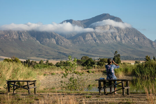 Bird watcher next to a dam with a mountain in the background