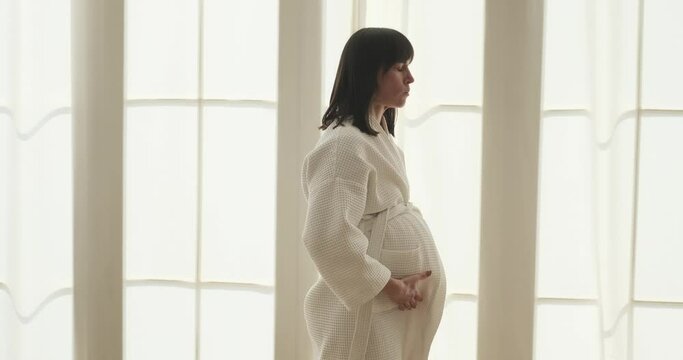 Focused expectant mother is experiencing contractions in the bedroom. Her determined expression reflects her strength and resilience as she navigates through the challenges of labor.