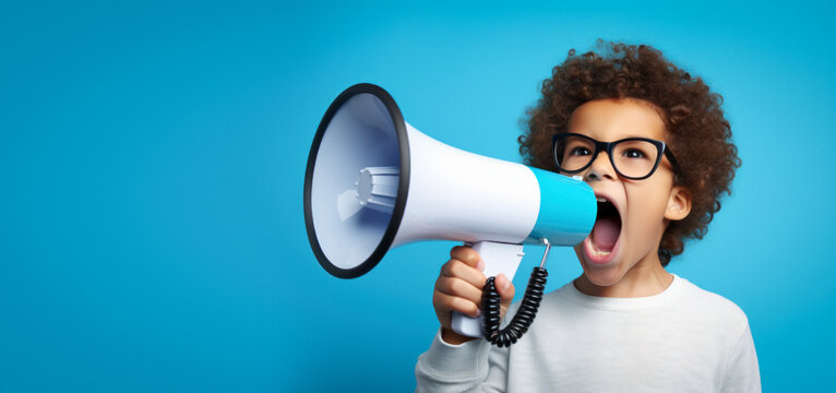 An African American boy with glasses is energetically shouting through a megaphone against a blue background,to deliver a message loud and clear, discounts, offers, copy space - Powered by Adobe