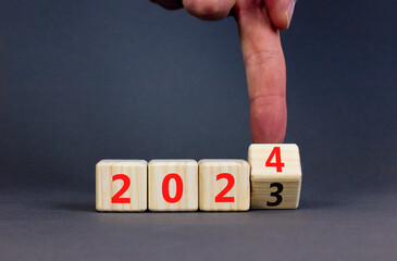 2024 happy new year symbol. Wooden cubes with number 2023 and 2024. Beautiful grey table grey background, copy space. Businessman hand. Business and 2024 happy new year concept.