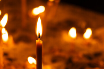 A lot of burning candles in the temple in the dark. The concept of religion, prayer and God.