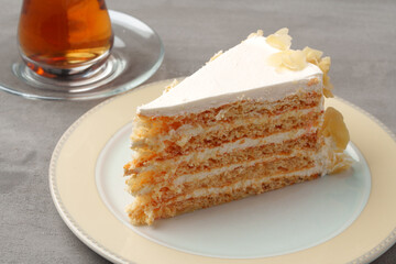 Piece of cake on plate with cup of tea on gray table
