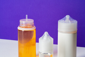 Electronic cigarettes liquid bottles on purple background