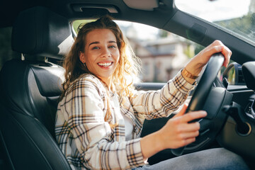 Happy smiling woman inside a car driving in the street