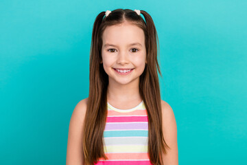 Closeup portrait of cute little school girl with two funny tails smiling good mood wear striped top isolated teal cyan color background