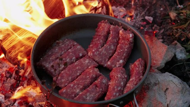 Close up video of preparing some meat in camping frying pan for dinner, wild cooking.