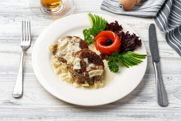 Two beef patties with sauce and fresh vegetables served on plate in cafe