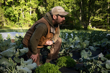 A young farmer hipster stands confidently in a lush green field, exuding a sense of connection to nature and a modern aesthetic. 