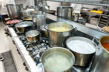 Food preparing in metal pots on the stove at professional kitchen