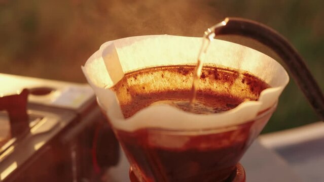 Close up video preparing pour over coffee outdoor in camping at sunrise.