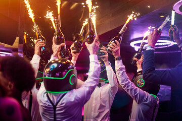 Bartenders in helmets holding champagne bottles with sparklers
