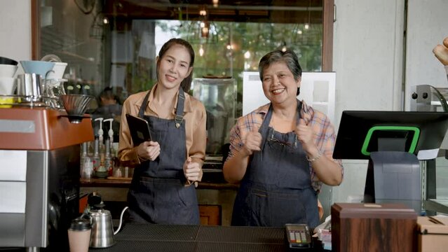 Joy of Asian  elderly mother with daughter Standing to take orders in front of coffee shop, which is their own bakery. Mother's daughter dancing in front of the counter in a good mood that sells well