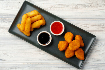 Fried snacks platter with sauce on gray wooden table