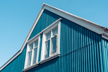 Blue building wall with a window and gabled roof on a sunny day, taken in Iceland, downtown Reykjavik