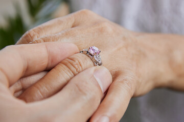 Close Up Side View Man Wearing Pink Wedding Ring in Ring Finger of Woman