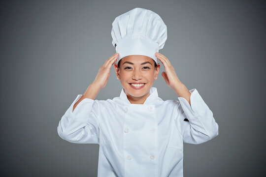 Portrait of young chef adjusting her hat.