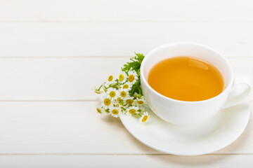Chamomile tea on a white table. Delicious tonic, soothing and relaxing chamomile tea with chamomile flowers, honey and lemon. Herbal tea for immunity. Close-up.Place for text.Copy space.