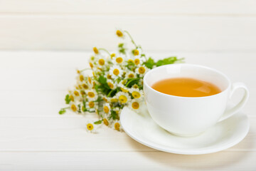Chamomile tea on a white table. Delicious tonic, soothing and relaxing chamomile tea with chamomile...