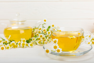Chamomile tea on a white table. Delicious tonic, soothing and relaxing chamomile tea with chamomile flowers, honey and lemon. Herbal tea for immunity. Close-up.Place for text.Copy space.