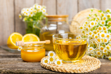 Chamomile tea on a brown table. Delicious tonic, soothing and relaxing chamomile tea with chamomile flowers, honey and lemon. Herbal tea for immunity. Close-up.Place for text.Copy space.