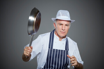 Portrait of mature butcher holding frying pan.