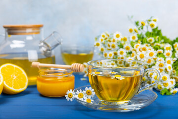 Chamomile tea on a blue table. Delicious tonic, soothing and relaxing chamomile tea with chamomile flowers, honey and lemon. Herbal tea for immunity. Close-up.Place for text.Copy space.