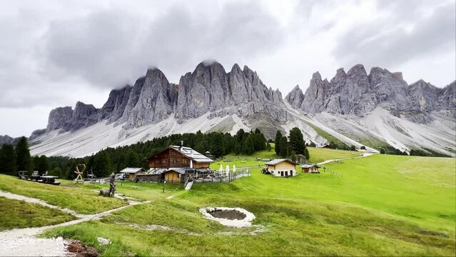 Imposing Dolomite landscape in Puez Odle Nature Park - view from alpine plateau with wooden houses and green meadows