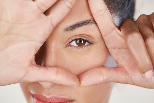 Portrait of woman looking through fingers.