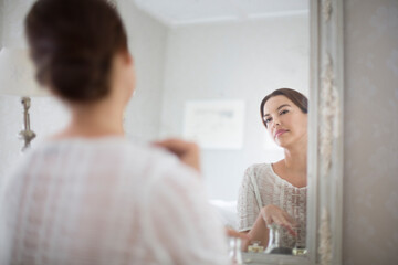 Mid adult woman looking at herself in mirror.