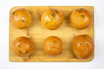Freshly baked buns with herbs.Fresh pastries. Fresh,tasty fragrant round buns,isolated.Buns with garlic and dill for the first course on a baking wooden board for serving dishes.