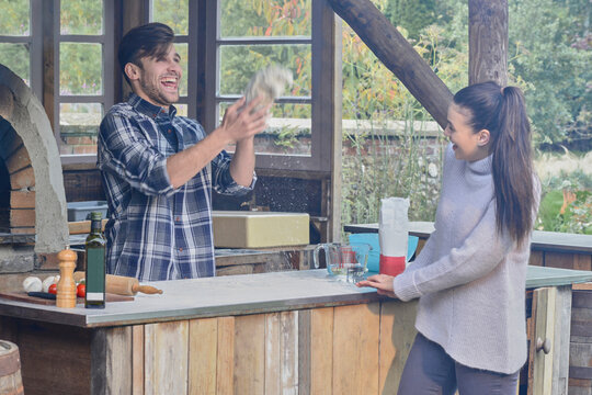 Young couple cooking in outdoor kitchen together.