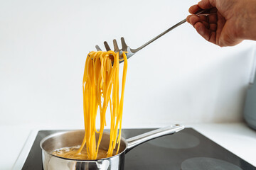 man cooks pasta spaghetti at home in kitchen.
