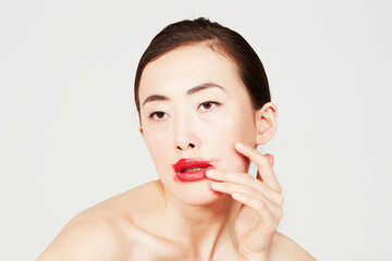 Young woman smearing red lipstick
