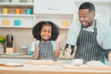 Obraz na płótnie Canvas Kind African american parents teaching their adorable daughter how to cook healthy food, free space of kitchen, Happy black people family preparing healthy food in kitchen together