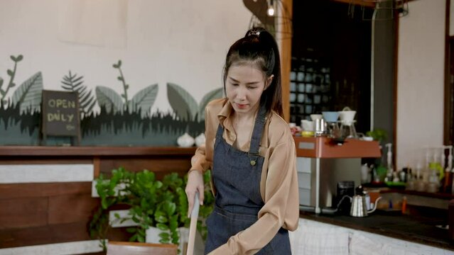Portrait, Asian working women, wear apron at all times while cleaning cafe, which is their own cafe, woman holding mop clean floor in bakery, after taking orders store is already closed in evening.